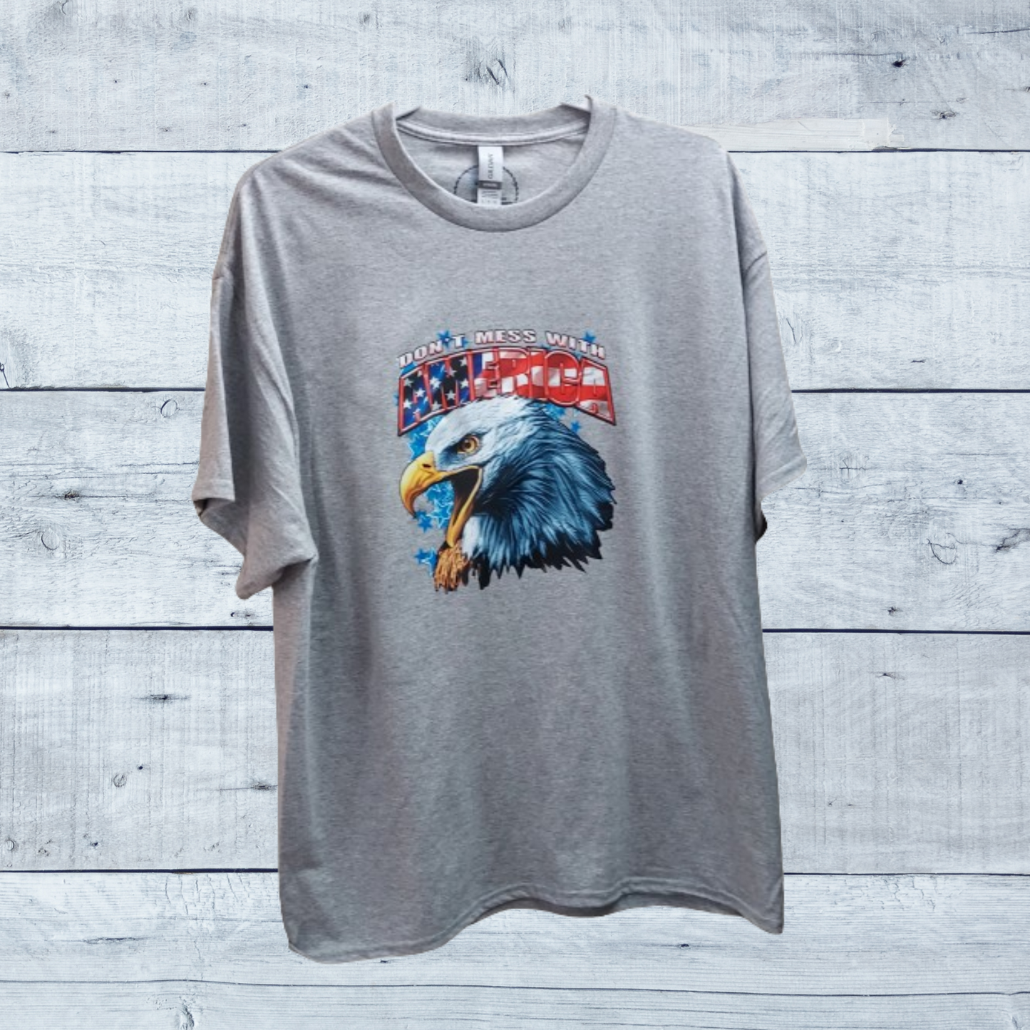 Show your patriotic pride with our "Don't Mess With America" t-shirt! Crafted from a premium 50/50 blend of cotton and polyester for unmatched comfort and durability. The classic gray hue complements the bold eagle head graphic emblazoned across the chest, symbolizing strength, freedom, and resilience.