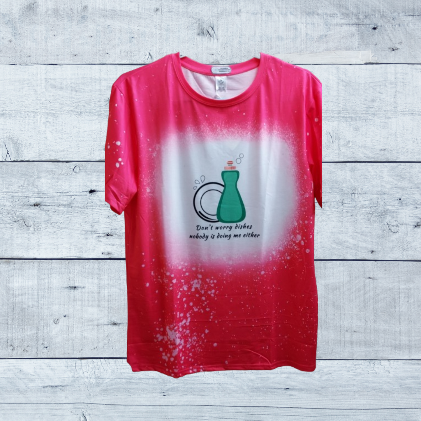 Uncertain about doing the dishes? Don't worry - with this soft, comfy t-shirt you won't have to shell out any sort of effort at all! Our vibrant bright pink faux bleached tee featuring the cheeky "Don't Worry Dishes Nobody Is Doing Me Either" —a must-have for those who appreciate a touch of humor and style in their wardrobe. This tee isn't just about looks; it's crafted for comfort and durability, using high-quality materials that ensure a soft feel against your skin and long-lasting wear