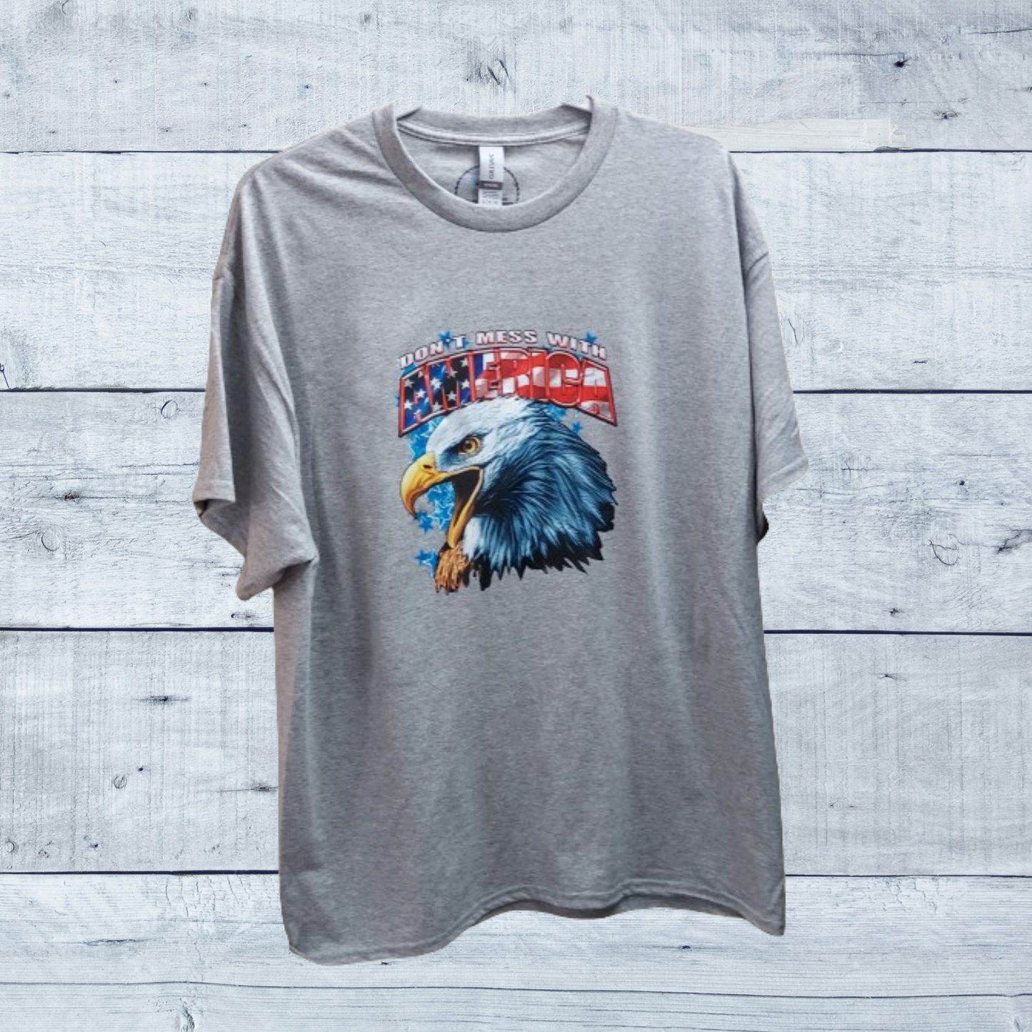 Show your patriotic pride with our "Don't Mess With America" t-shirt!  &nbsp;Crafted from a premium 50/50 blend of cotton and polyester for unmatched comfort and durability. The classic gray hue complements the bold eagle head graphic emblazoned across the chest, symbolizing strength, freedom, and resilience.